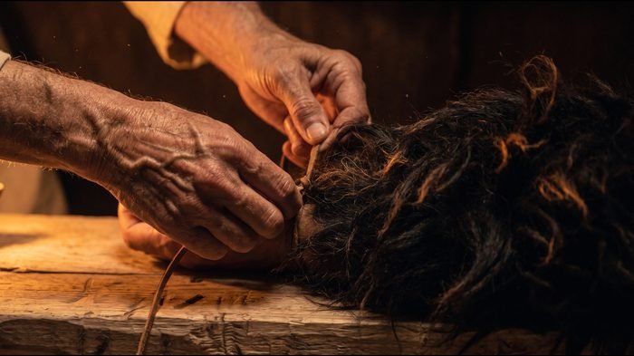 Unas manos atan piel de cabrito a la luz de un candil